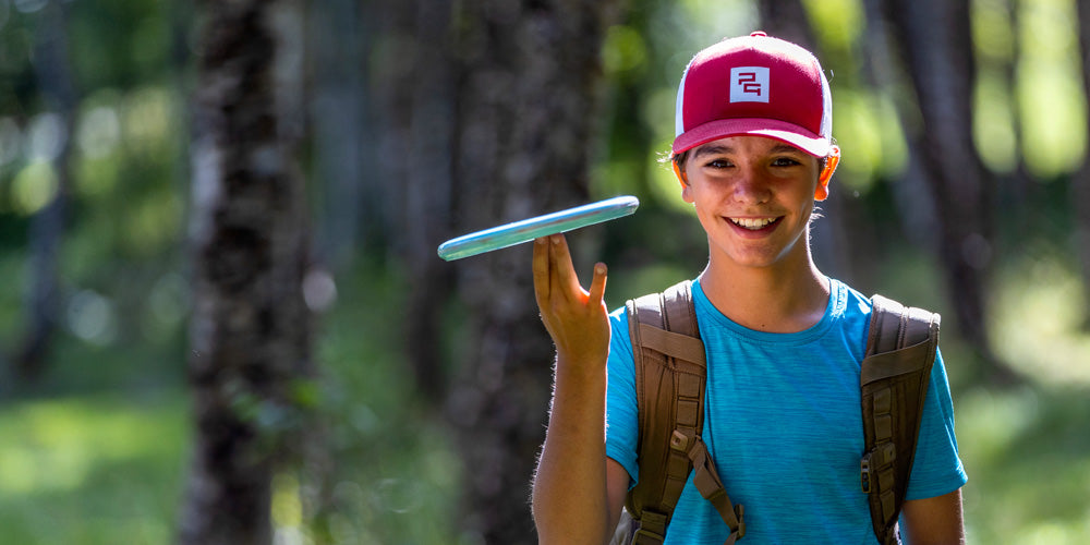 Young boy playing disc golf spinning a disc on his finger