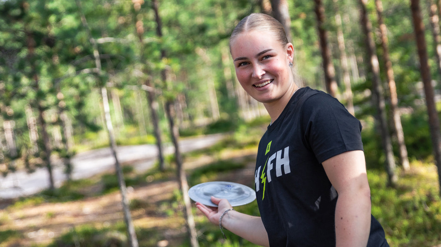Female playing disc golf in the woods